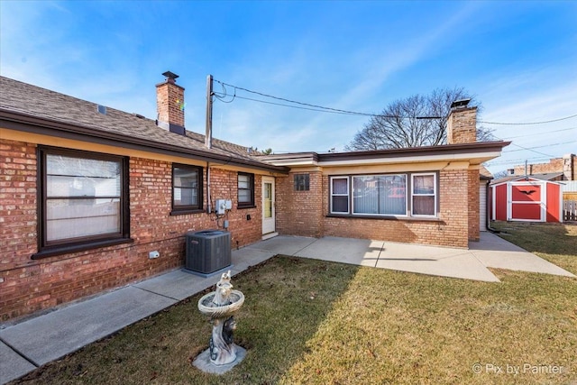 rear view of house with a storage shed, a patio, a yard, and a chimney