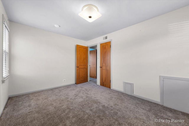 carpeted empty room with visible vents and baseboards