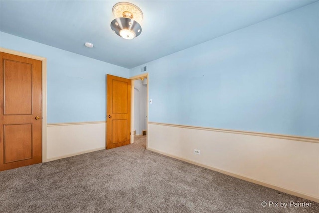 carpeted spare room featuring visible vents and baseboards