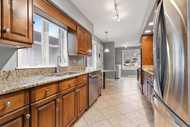 kitchen with light tile patterned floors, brown cabinets, appliances with stainless steel finishes, and a sink