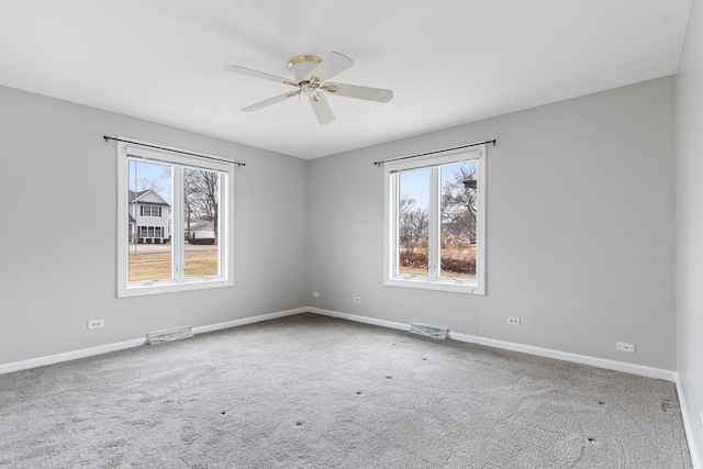 carpeted spare room featuring baseboards, plenty of natural light, visible vents, and ceiling fan