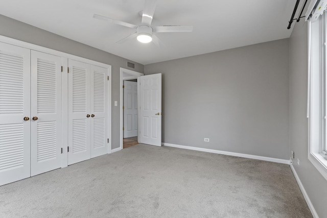 unfurnished bedroom featuring carpet flooring, ceiling fan, baseboards, and visible vents