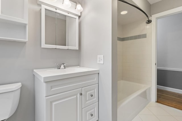 full bath featuring toilet, tile patterned flooring, baseboards, bathing tub / shower combination, and vanity