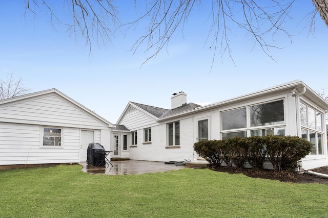 back of property with a patio, a lawn, and a chimney