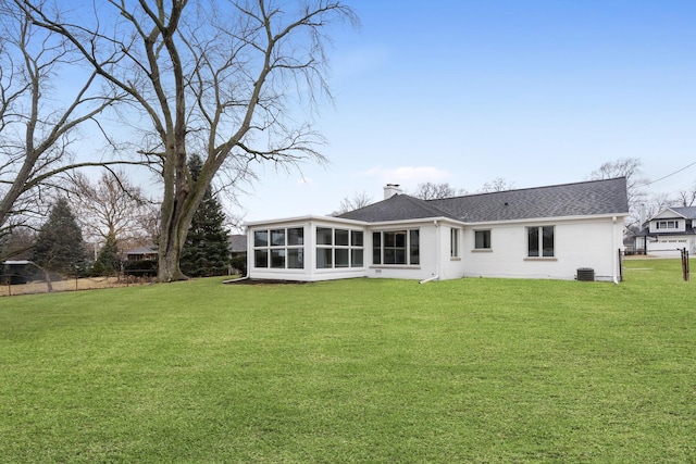 rear view of house featuring a shingled roof, a yard, a sunroom, and a chimney