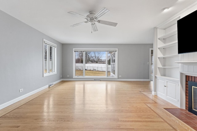 unfurnished living room with light wood-type flooring, baseboards, a ceiling fan, and a fireplace