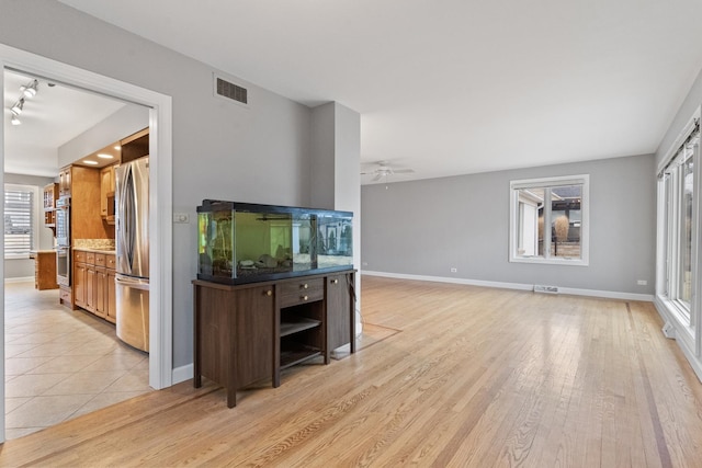 living area featuring light wood-type flooring, visible vents, and baseboards