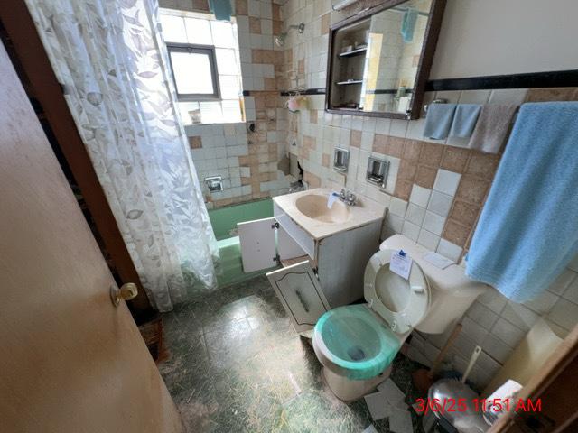 full bathroom featuring tile walls, vanity, toilet, and shower / tub combo with curtain