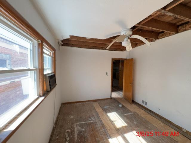 empty room with light wood-type flooring, visible vents, baseboards, and cooling unit