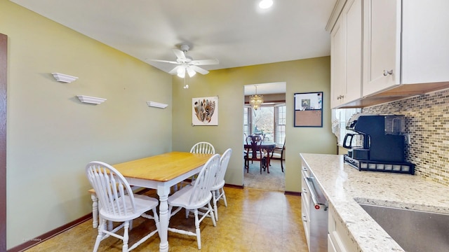 dining space featuring baseboards, ceiling fan, and a wood stove