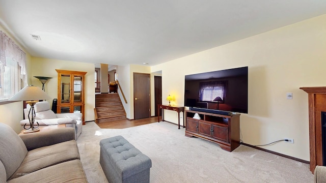 living room with light carpet, plenty of natural light, stairs, and visible vents