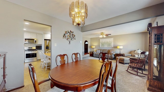 dining area featuring arched walkways, light colored carpet, and a ceiling fan