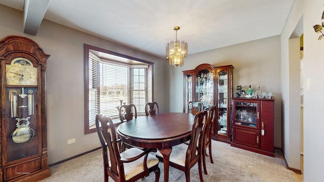 dining space with an inviting chandelier, light colored carpet, and baseboards