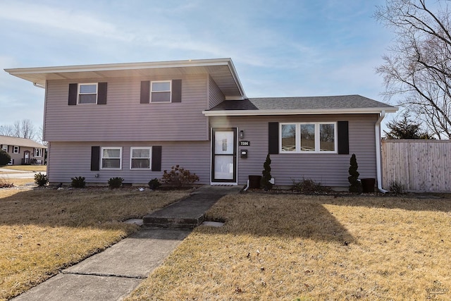 split level home featuring a front yard and fence