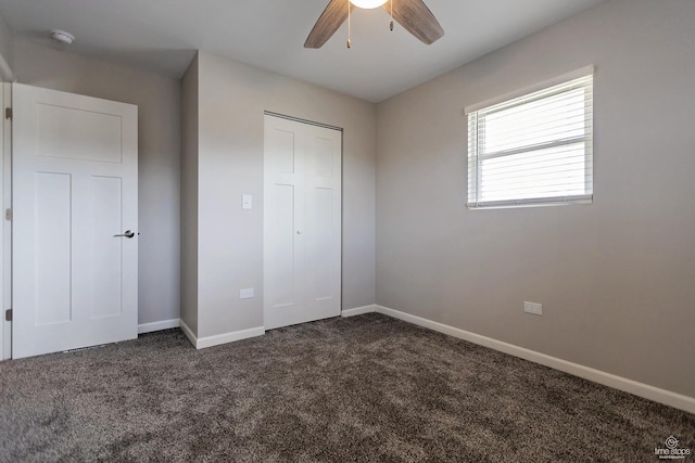 unfurnished bedroom with a ceiling fan, baseboards, dark colored carpet, and a closet