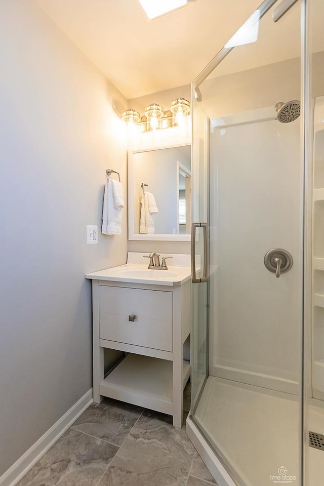 full bath featuring a shower stall, vanity, and baseboards