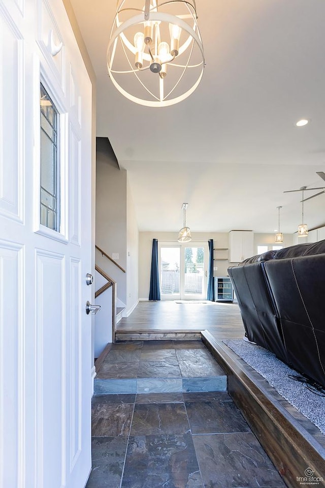 entrance foyer with stairs, a notable chandelier, and stone tile flooring