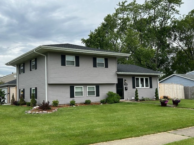 split level home with a front lawn and fence