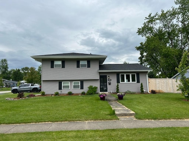 split level home featuring a front lawn and fence