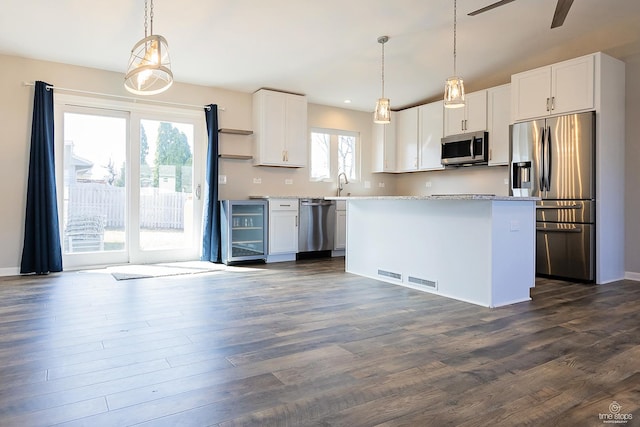 kitchen with a sink, a center island, beverage cooler, stainless steel appliances, and dark wood-style flooring