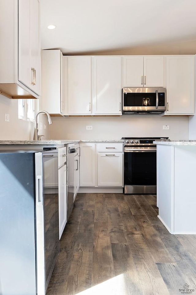 kitchen with recessed lighting, white cabinets, appliances with stainless steel finishes, and dark wood-type flooring