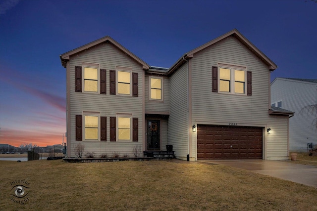 traditional-style home with concrete driveway, an attached garage, fence, and a front lawn