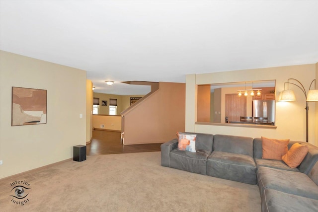 carpeted living room with stairway and an inviting chandelier