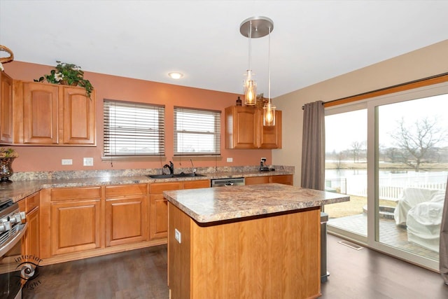 kitchen with a center island, dark wood finished floors, light countertops, appliances with stainless steel finishes, and a sink