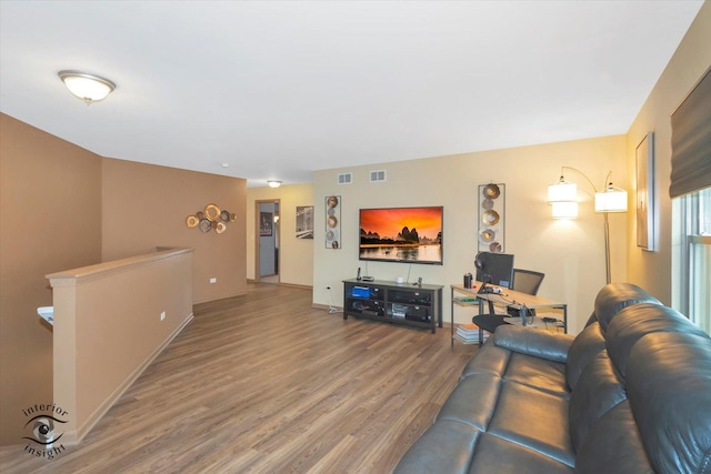 living area with wood finished floors, visible vents, and baseboards