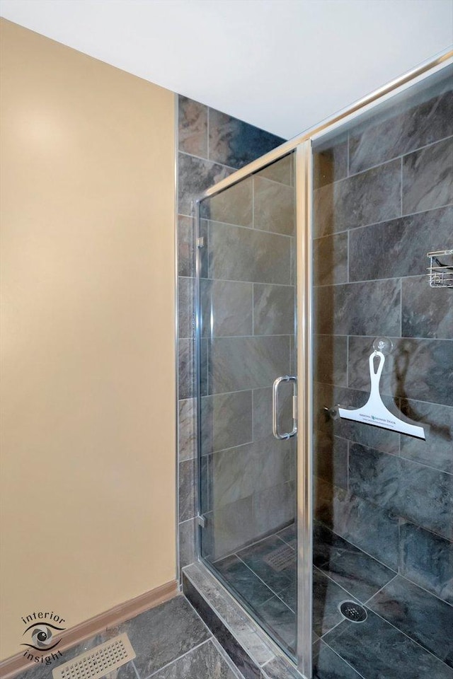 full bath with tile patterned flooring, a stall shower, and baseboards