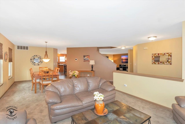 living area with light colored carpet, visible vents, and baseboards