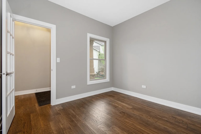 spare room with baseboards and dark wood-style flooring