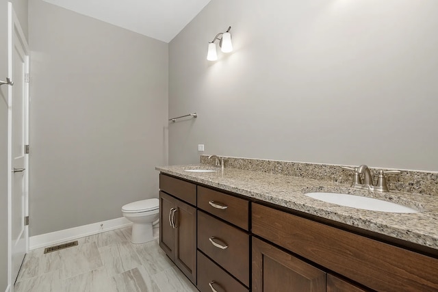 bathroom featuring double vanity, visible vents, toilet, and a sink