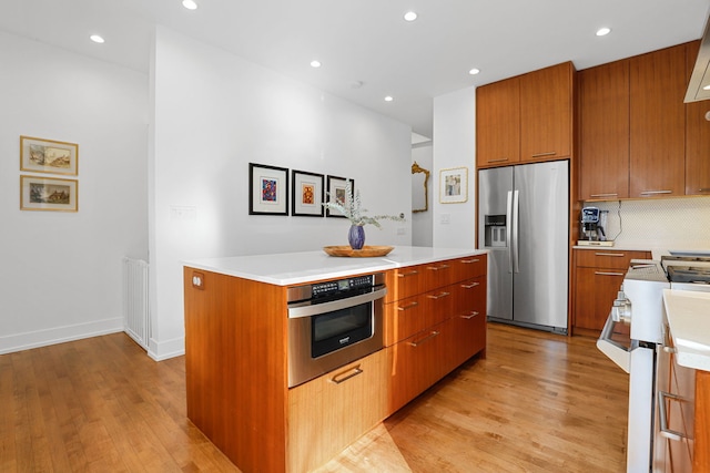 kitchen with brown cabinets, a kitchen island, light wood finished floors, and stainless steel appliances