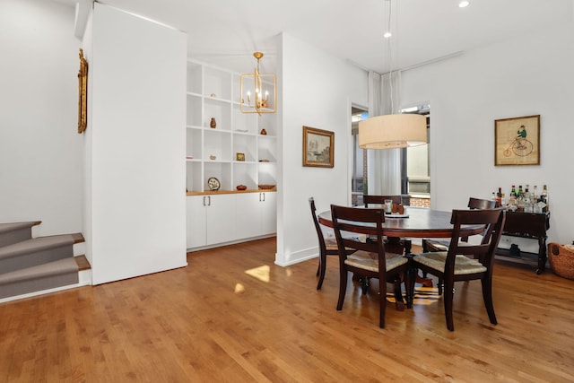 dining area featuring a chandelier, stairway, and wood finished floors