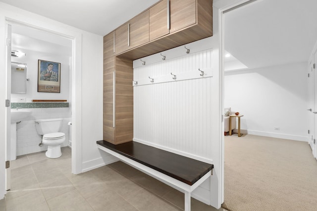 mudroom featuring light tile patterned floors, baseboards, light colored carpet, and tile walls