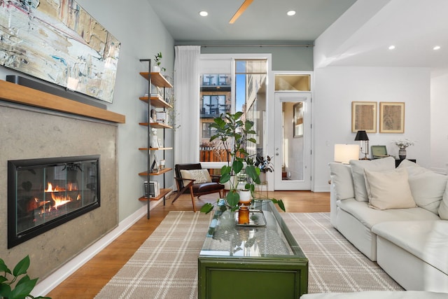 living area featuring recessed lighting, baseboards, wood finished floors, and a fireplace