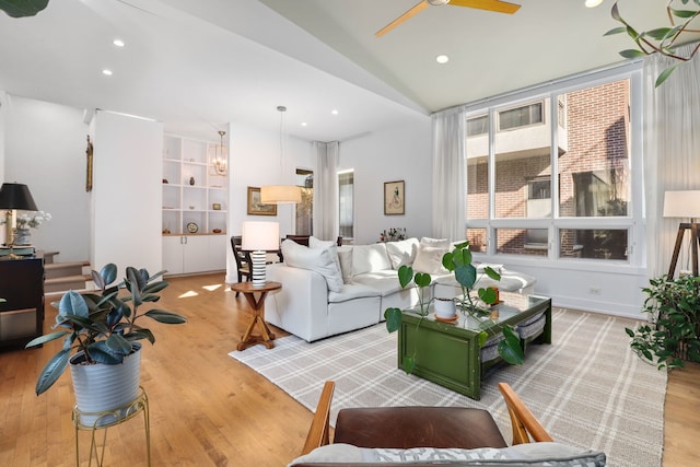 living room with built in shelves, wood finished floors, recessed lighting, lofted ceiling, and ceiling fan