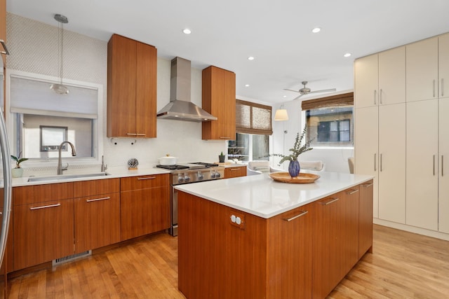 kitchen with visible vents, light countertops, high end range, wall chimney exhaust hood, and a sink