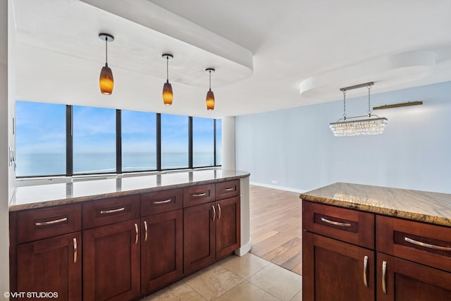 kitchen featuring a wall of windows, light stone counters, baseboards, and pendant lighting