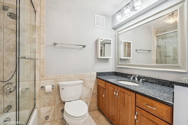 bathroom with tile patterned floors, visible vents, toilet, tile walls, and vanity