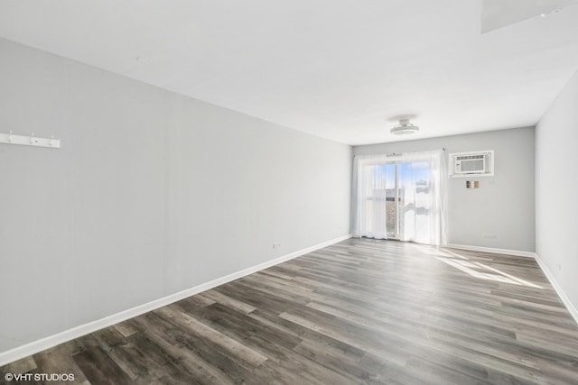 empty room with baseboards, an AC wall unit, and wood finished floors