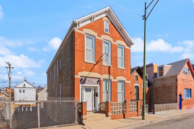 view of front of home featuring brick siding and fence