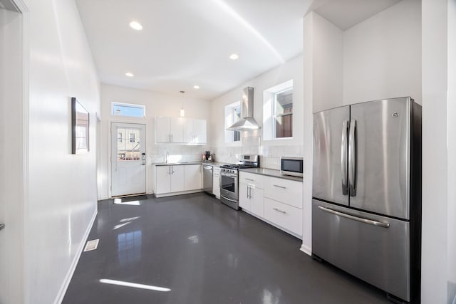 kitchen with baseboards, wall chimney range hood, stainless steel appliances, white cabinetry, and modern cabinets