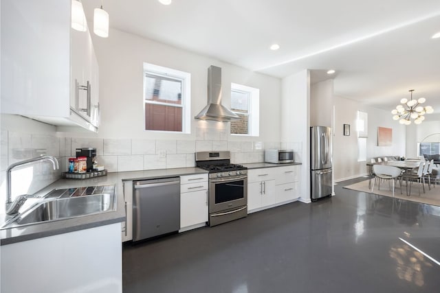 kitchen with tasteful backsplash, appliances with stainless steel finishes, white cabinetry, wall chimney exhaust hood, and a sink