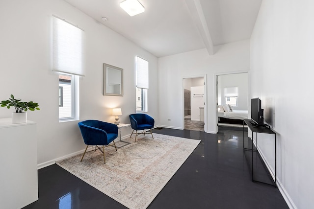 living area with baseboards and beam ceiling