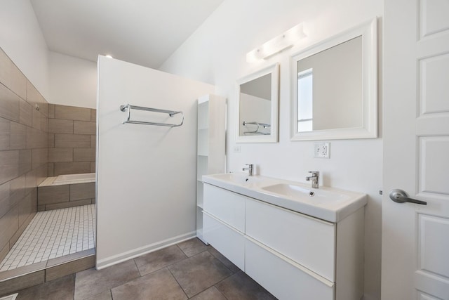 full bathroom with tile patterned floors, double vanity, a tile shower, and a sink