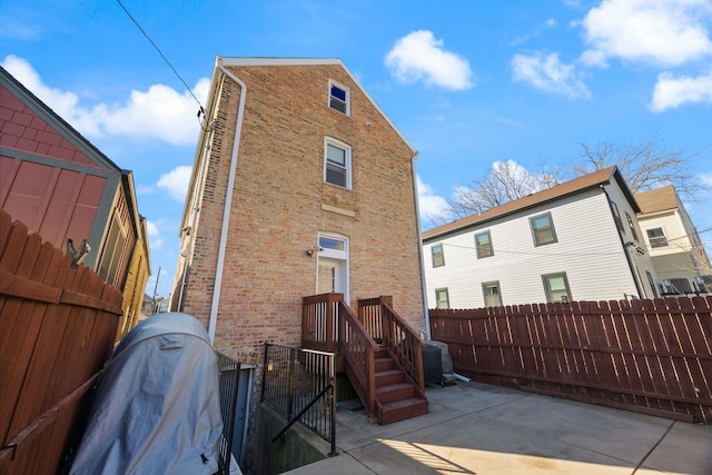 rear view of property with a patio, brick siding, and fence