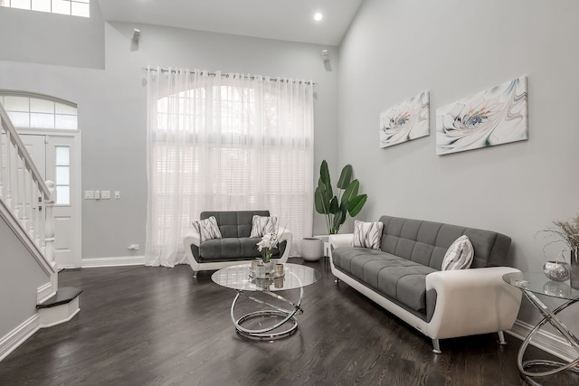 living area with stairway, wood finished floors, baseboards, and a wealth of natural light