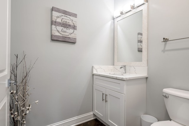 bathroom with toilet, vanity, and baseboards